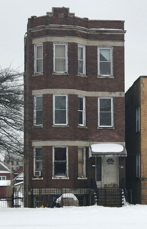 A tall brick building with a white awning and snow on the ground.