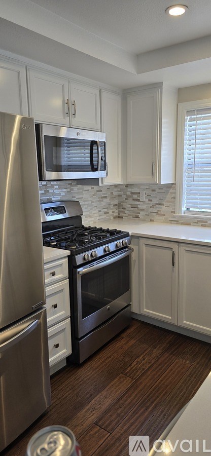 A kitchen with white cabinets and a stainless steel refrigerator.