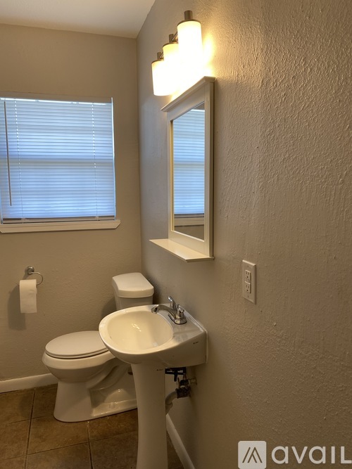 A bathroom with a toilet, sink, and mirror.