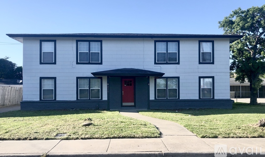 A white house with a red door and black windows.