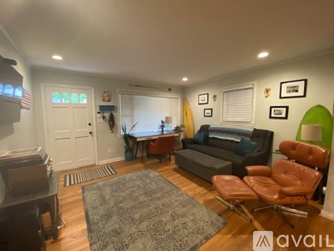 A living room with a grey couch, a brown leather chair, and a rug on the floor.