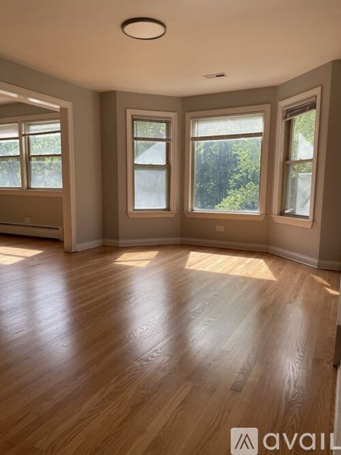 A room with wooden floors and three windows.