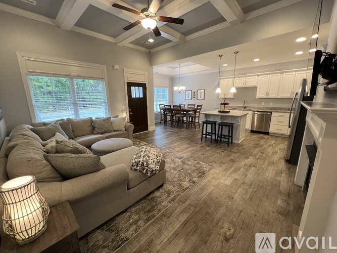 A well-lit living room with a grey sofa and a wooden floor.