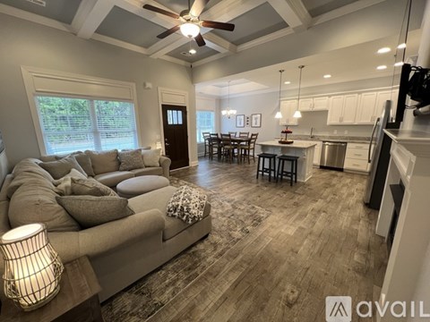 A well-lit living room with a grey sofa and a wooden floor.