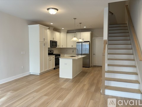 A kitchen with white cabinets and a wooden floor.