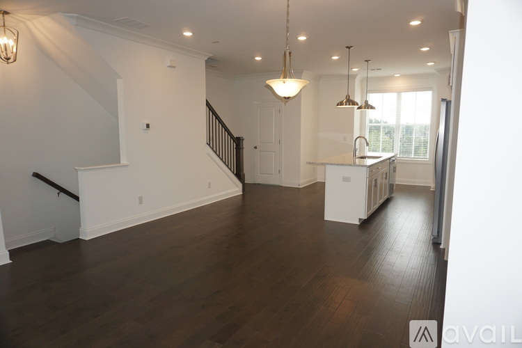A spacious living room with a staircase and a kitchen area.