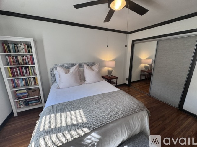 A bedroom with a large bed and a bookshelf filled with books.