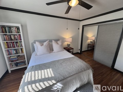 A bedroom with a large bed and a bookshelf filled with books.