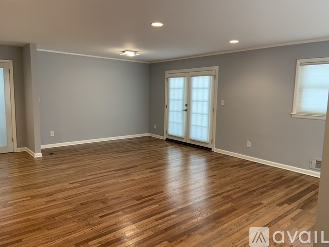A spacious room with wooden flooring and a large window.