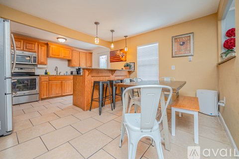 A kitchen with a white chair and a white fridge.