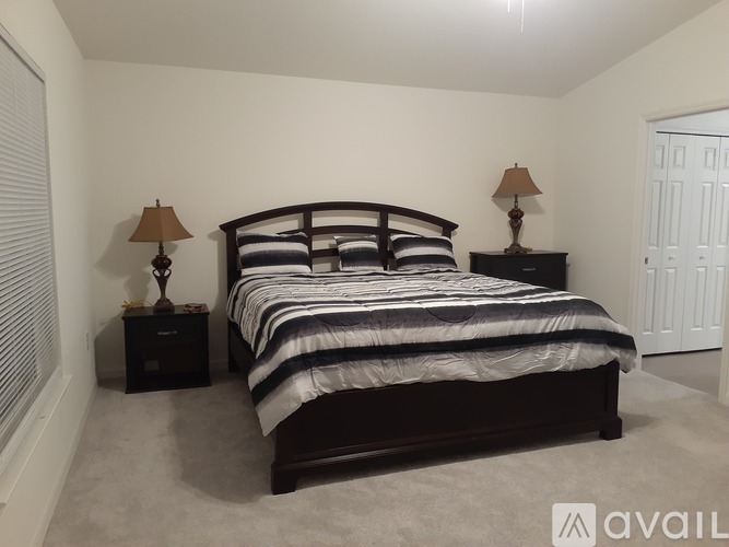 A bedroom with a large bed and two lamps on nightstands.