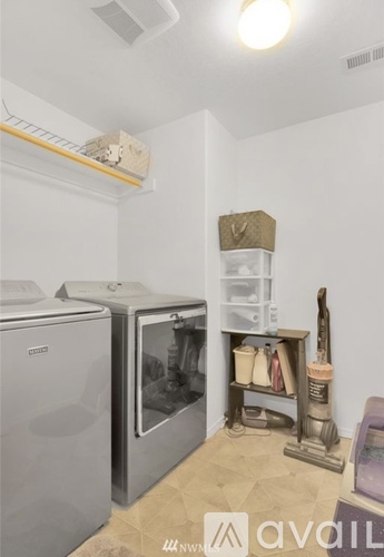 A kitchen with a white wall and a white fridge.