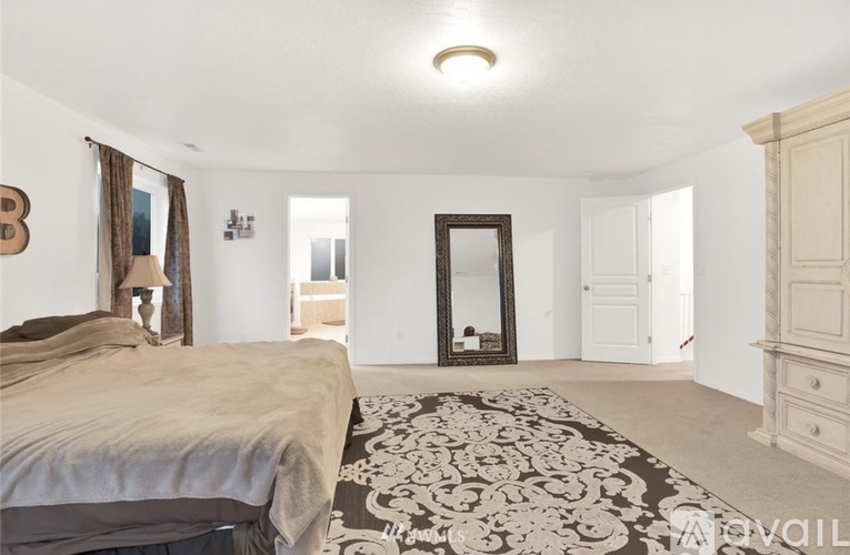 A bedroom with a large bed and a dresser.