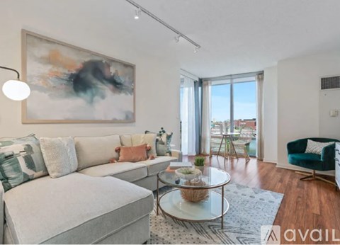 A living room with a large painting on the wall and a sofa with throw pillows.