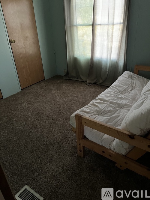 A bedroom with a bed, carpet, and a door.