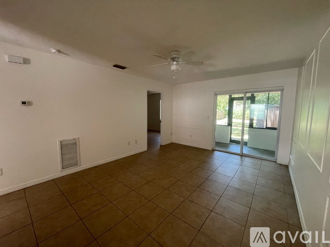 A spacious room with tiled flooring and a sliding glass door leading outside.