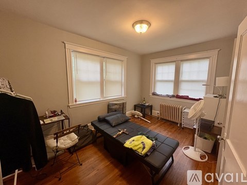 A living room with a black couch and a wooden floor.