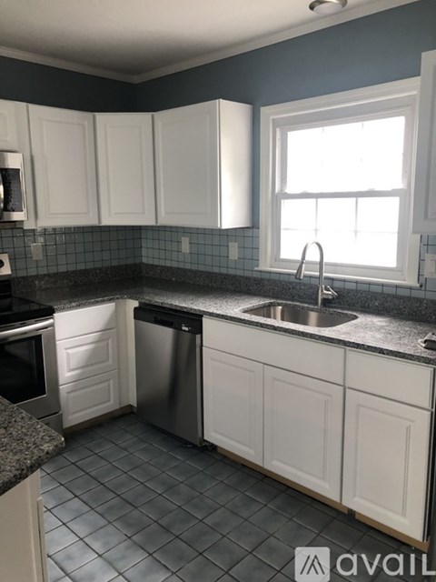 A kitchen with white cabinets and a black counter top.