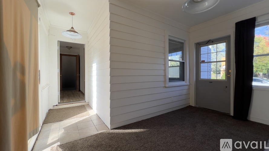A room with a carpeted floor and a window with a view of the outside.
