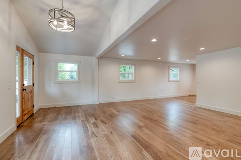 A spacious room with wooden flooring and a hanging light fixture.