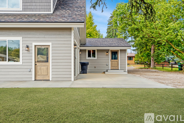 A house with a grey exterior and a brown door is available for rent.