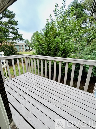 A wooden deck with a railing and trees in the background.