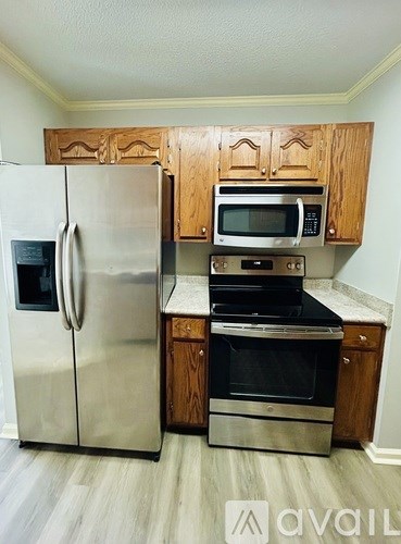 A kitchen with a stainless steel refrigerator and oven, and wooden cabinets.