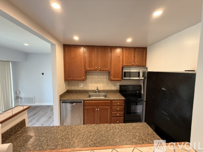 A kitchen with brown cabinets and black appliances.