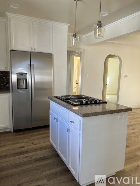 A kitchen with a stainless steel refrigerator and white cabinets.