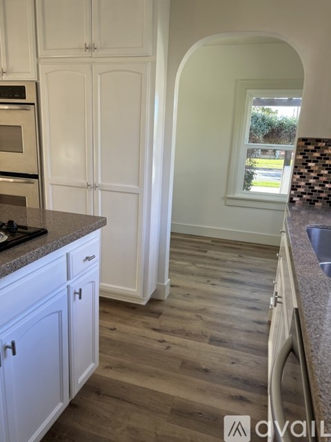 A kitchen with white cabinets and a window.