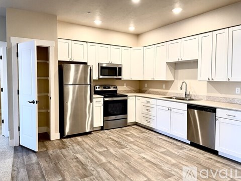 A kitchen with white cabinets and a wooden floor.