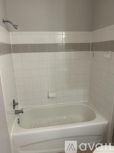 A white bathtub with a shower head above it.