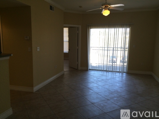 A room with a ceiling fan and sliding glass doors leading to a balcony.