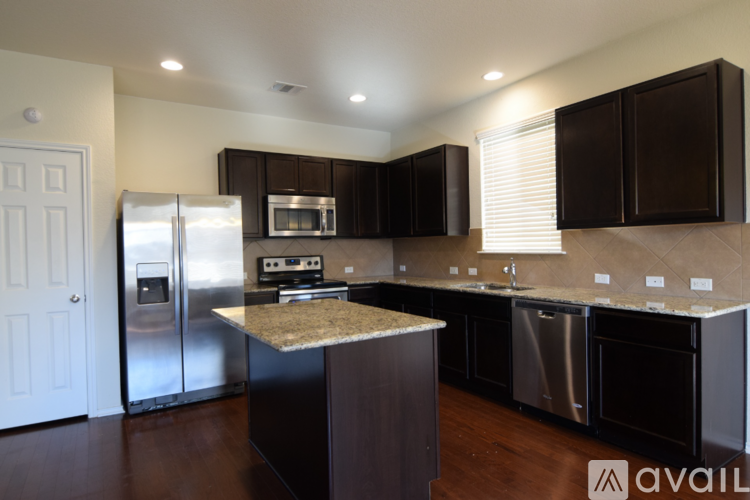A kitchen with dark brown cabinets and stainless steel appliances.