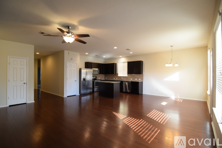 A spacious living room with a ceiling fan and hardwood floors.