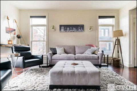 A living room with a grey sofa and black chairs.