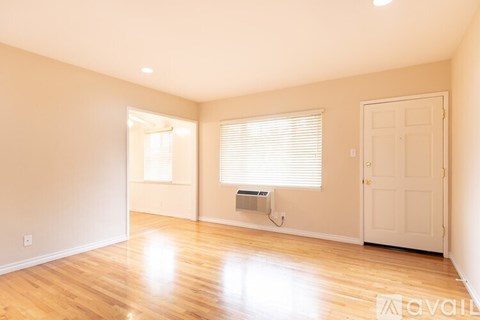 A room with wooden floors and a window with blinds.