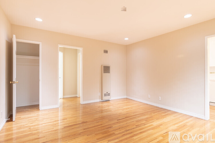 A spacious room with wooden floors and white walls.