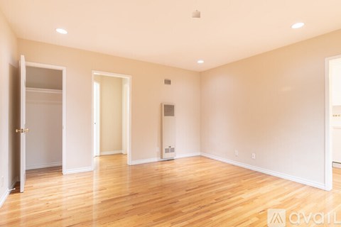 A spacious room with wooden floors and white walls.