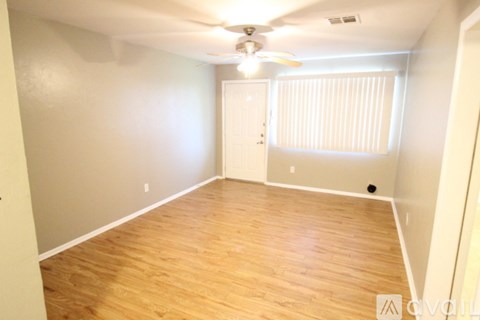 A room with wooden flooring and a ceiling fan.