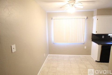 A room with a ceiling fan and a window with blinds.