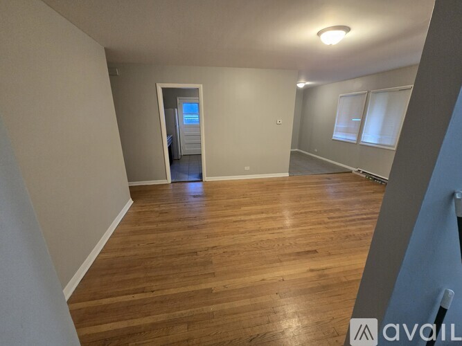 A spacious room with wooden flooring and a doorway leading to another room.