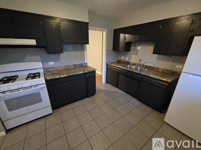 A kitchen with black cabinets and a white stove.