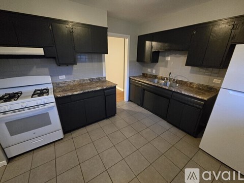 A kitchen with black cabinets and a white stove.