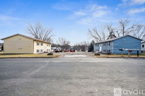 A parking lot with two houses and a car parked in front of the house on the right.