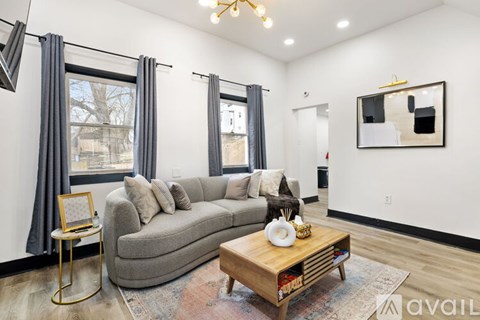 A living room with a grey couch, a wooden coffee table, and a painting on the wall.