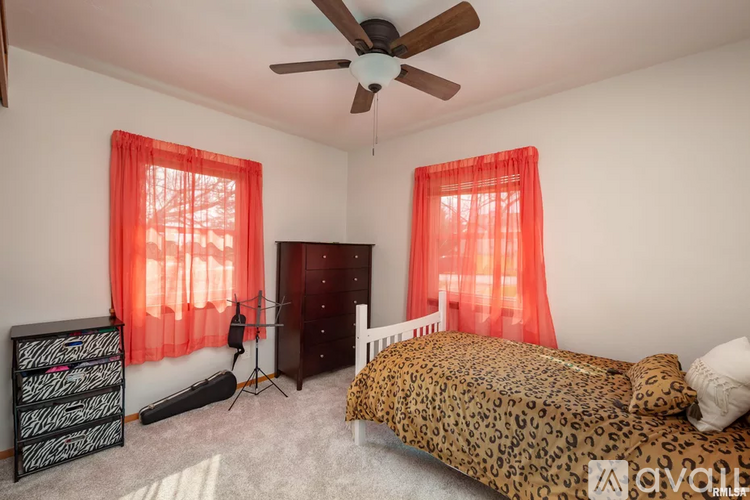 A bedroom with a leopard print bed and red curtains.