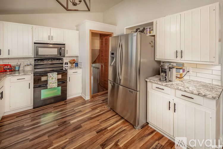 A kitchen with white cabinets and a wooden floor.