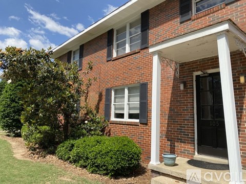 A red brick house with a black door and white columns.