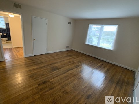 A room with wooden flooring and a window with blinds.